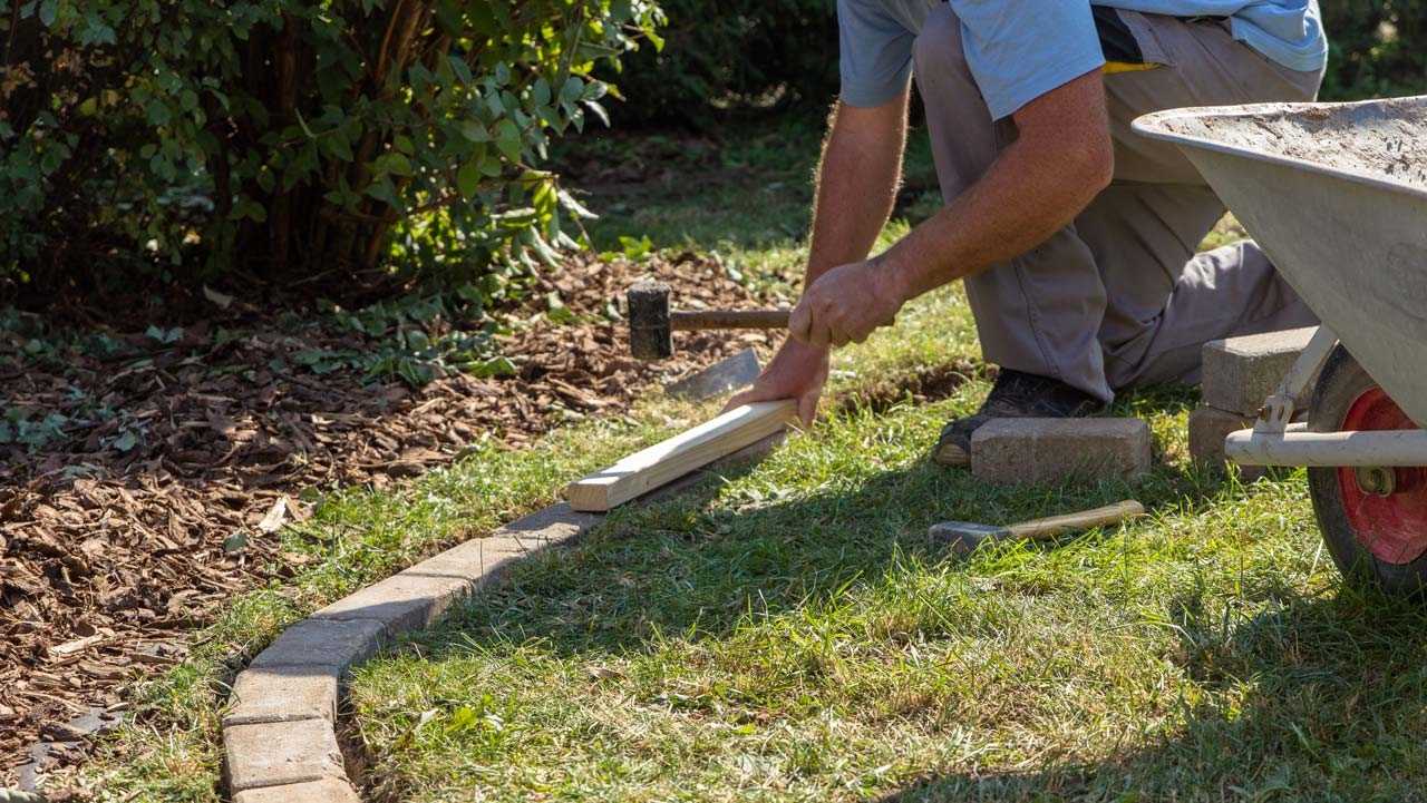 Person richtet Steine für eine Beeteinfassung aus