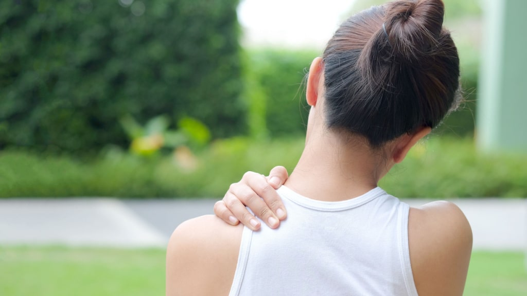 Frau hält sich im Garten den Nacken