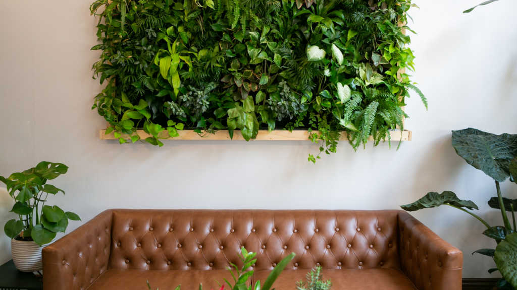 Bepflanzte Wand über einem braunen Ledersofa im Wohnzimmer