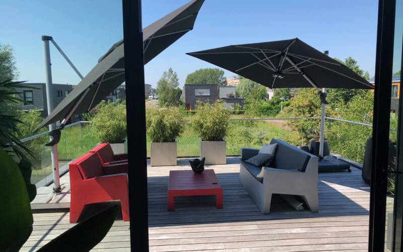 Zwei dunkle Ampelschirme über einer Terrasse