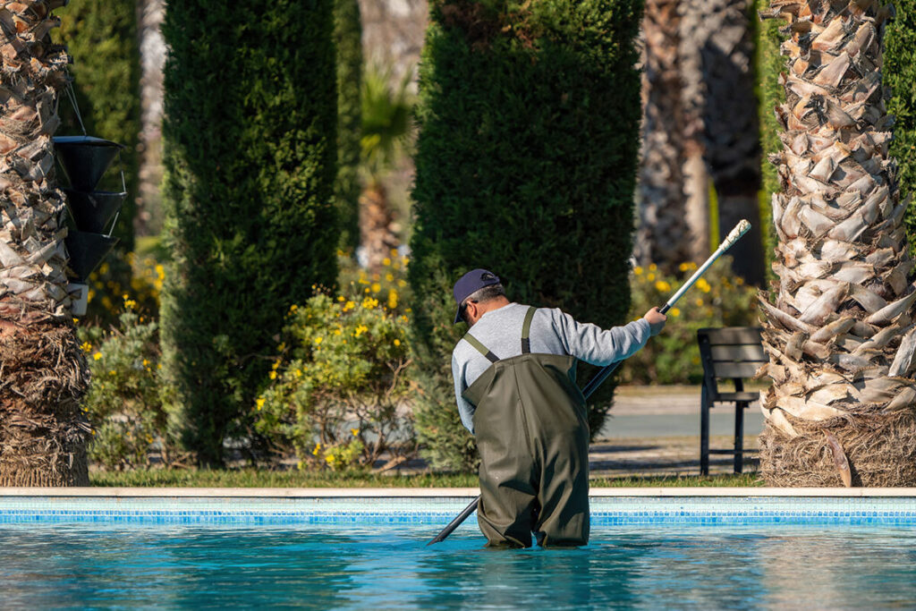 Person reinigt einen Swimmingpool