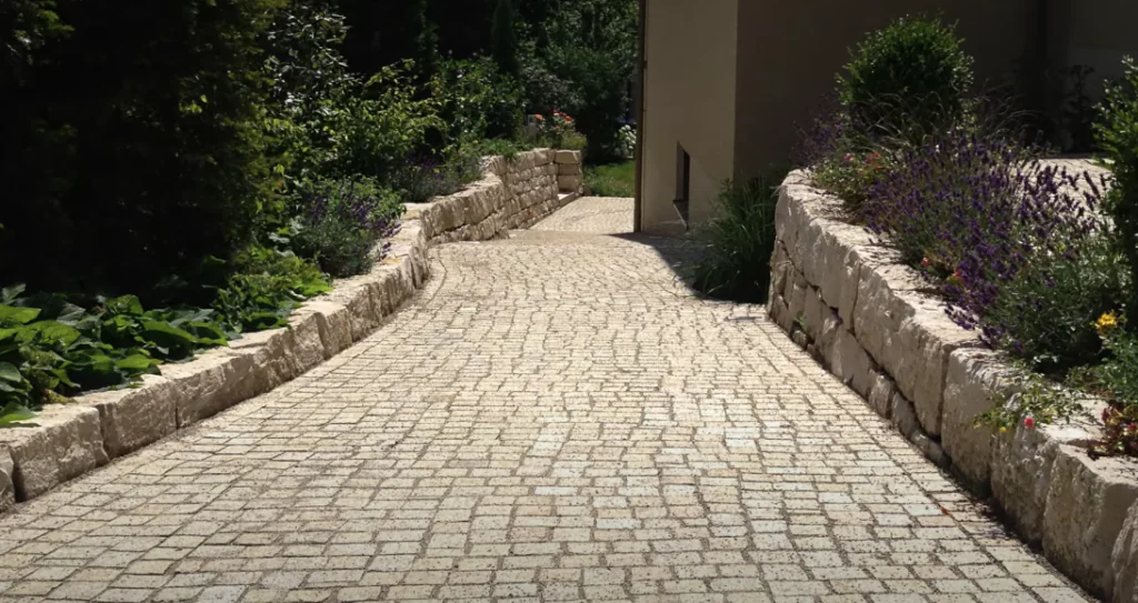 Gepflasterter Gartenweg mit Gefälle zwischen bepflanzten Natursteinmauern