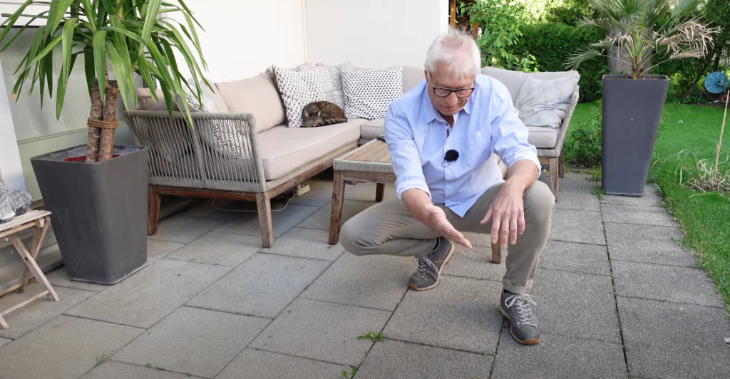 Mann kniet auf einer Terrasse aus grauen Platten