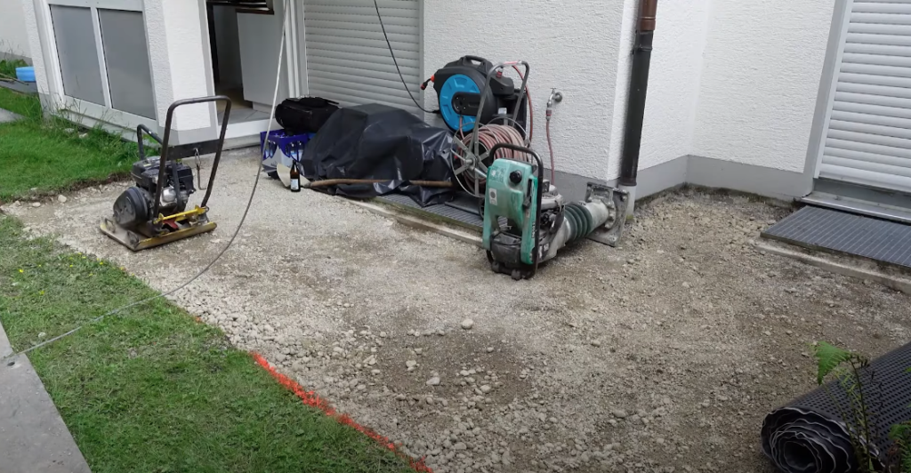 Rüttelplatten und Werkzeug auf dem vorbereiteten Unterbau einer Terrasse