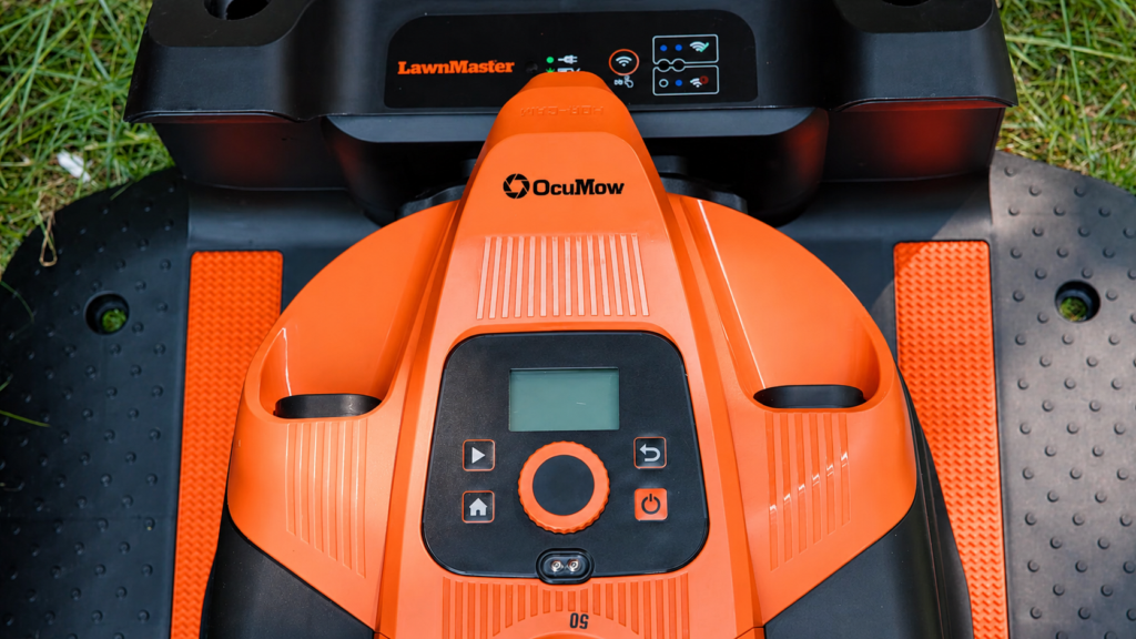 Bedienfeld des orangefarbenen LawnMaster OcuMow 18 auf der Ladestation