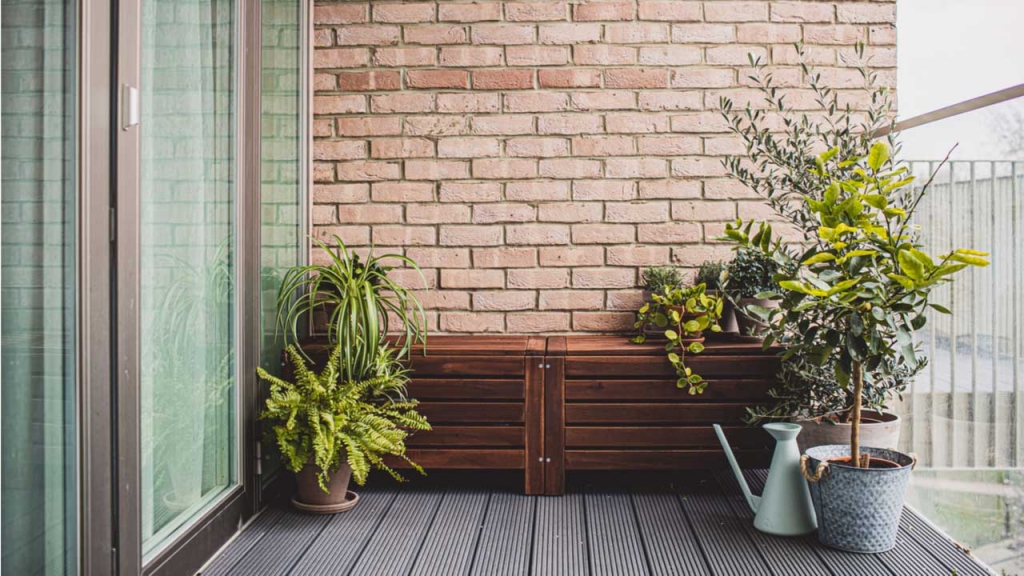 Balkon mit Kübelpflanzen, Holzschrank und Gießkanne