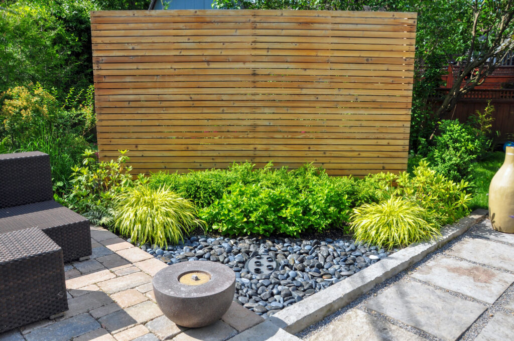 Horizontaler Sichtschutz aus Holzlatten in einem begrünten Garten