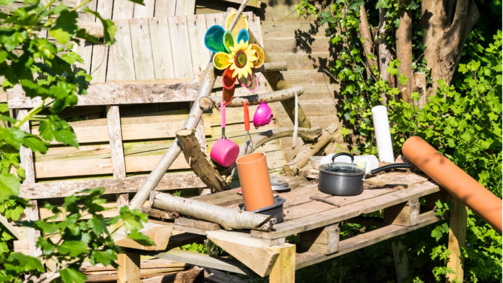Matschküche aus Holzpaletten mit Töpfen und Spielzeug im Garten