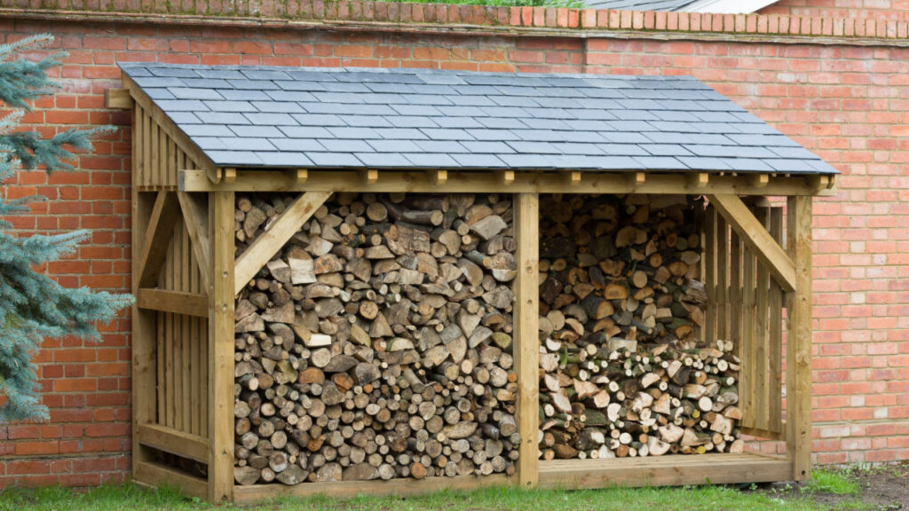 Holzunterstand mit Brennholz an einer Backsteinwand