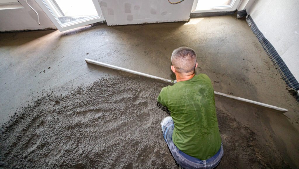 Handwerker glättet einen frisch eingebrachten Boden mit einer Richtlatte