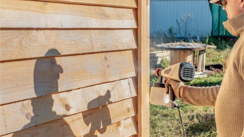 Mann sprüht Mittel ins Holz
