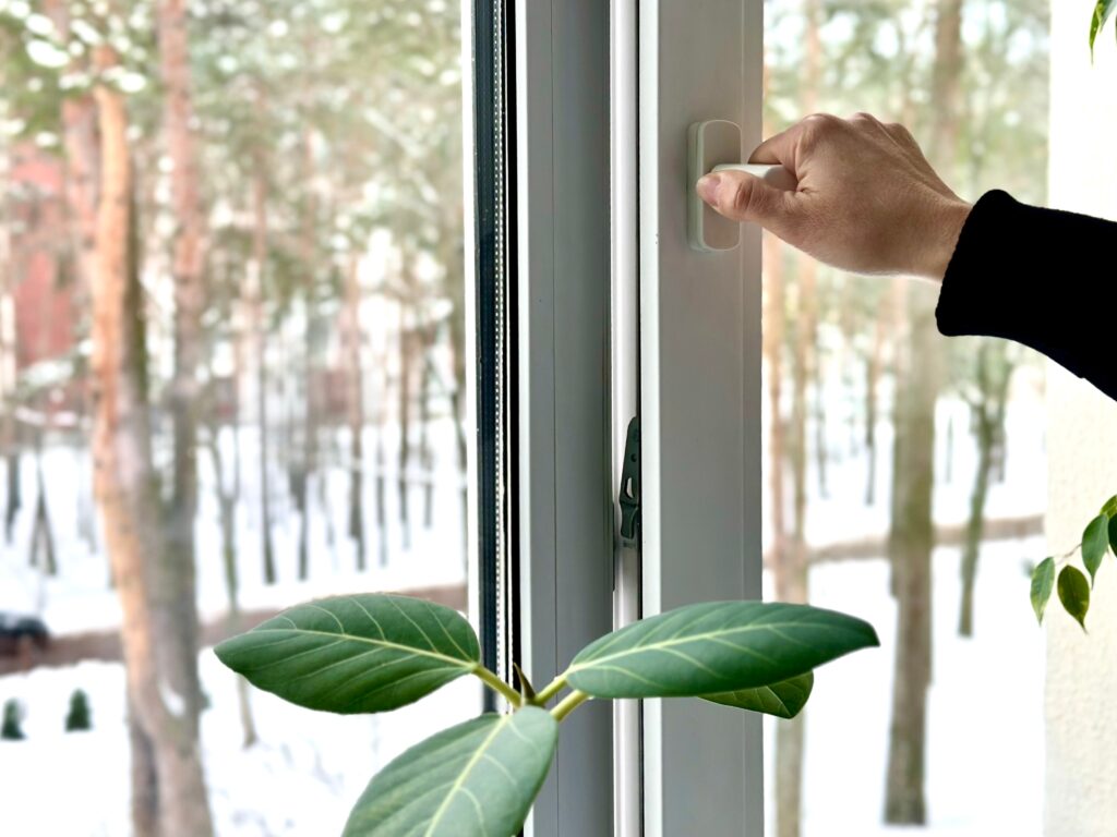 Hand schließt ein Fenster im Winter