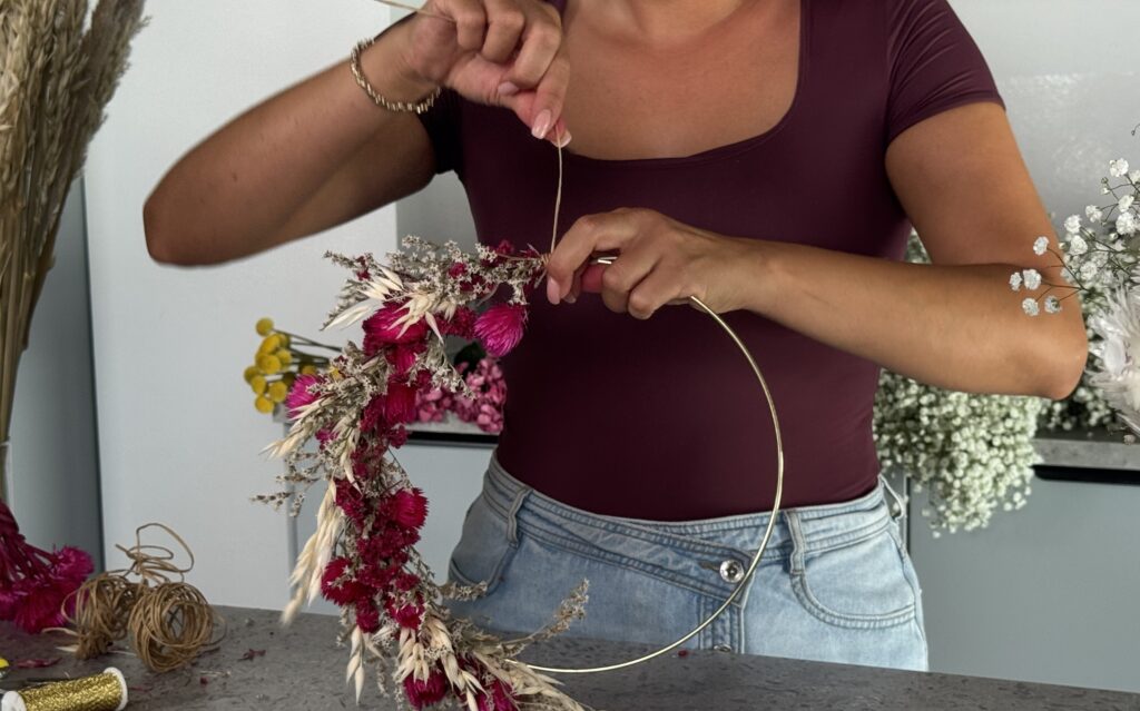 Frau bindet Trockenblumenkranz