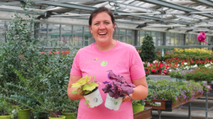 Frau im Gartenzentrum hält zwei Pflanzen